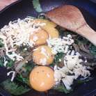 В остывший шпинат с луком разбить яйца, посолить, поперчить, добавить сыр (немного сыра оставить на посыпку), разболтать. 