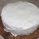Взбить оставшиеся сливки, постепенно добавляя сахарную пудру, и обмазать торт со всех сторон.